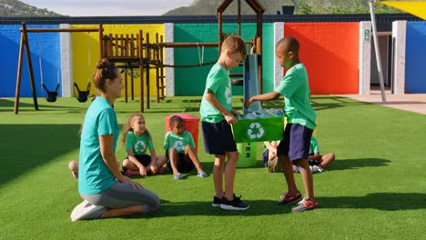 side view of caucasian female teacher teaching schoolkids about bottle recycle in the school playgro