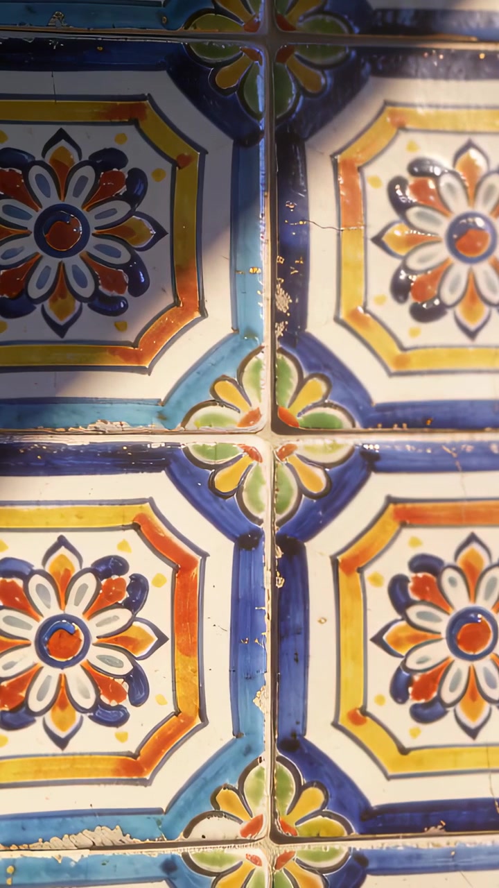 Video verticale: Telecamera che panoramica filmando piastrelle smaltate floreali su una parete, rivelando scheggiature della malta e segni di usura.