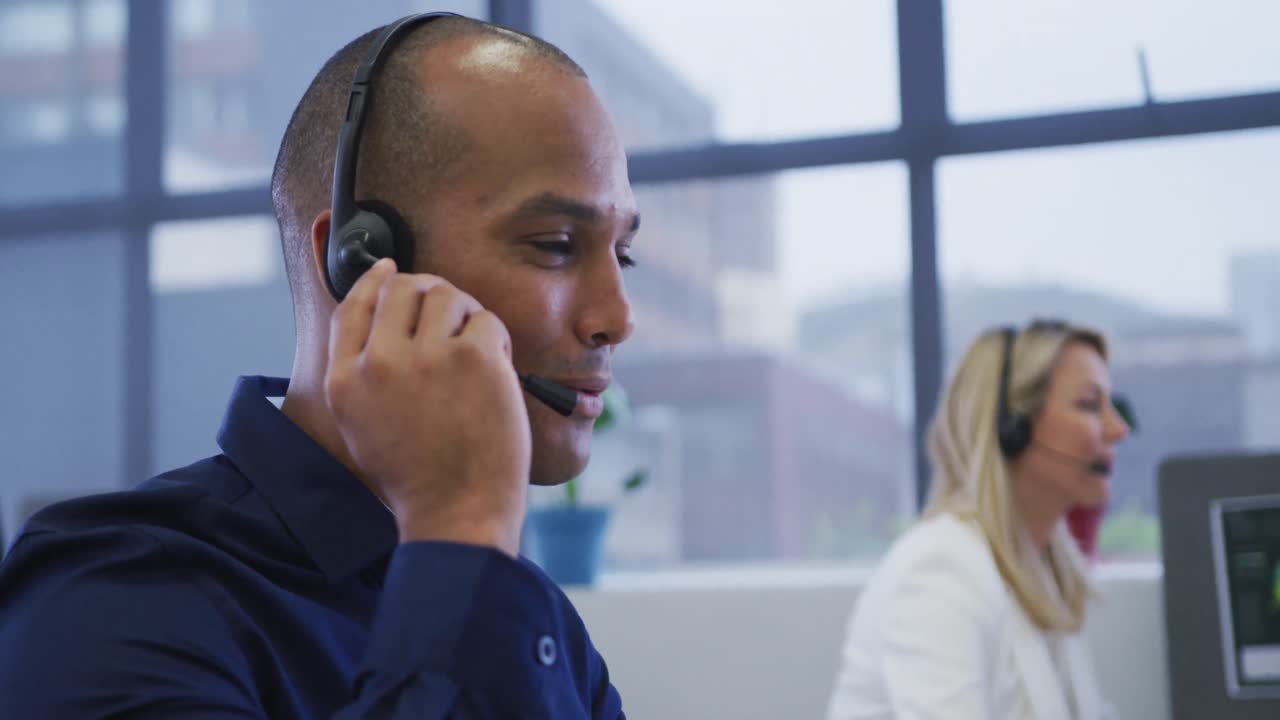 Diverse business people sitting using computers talking with phone headsets