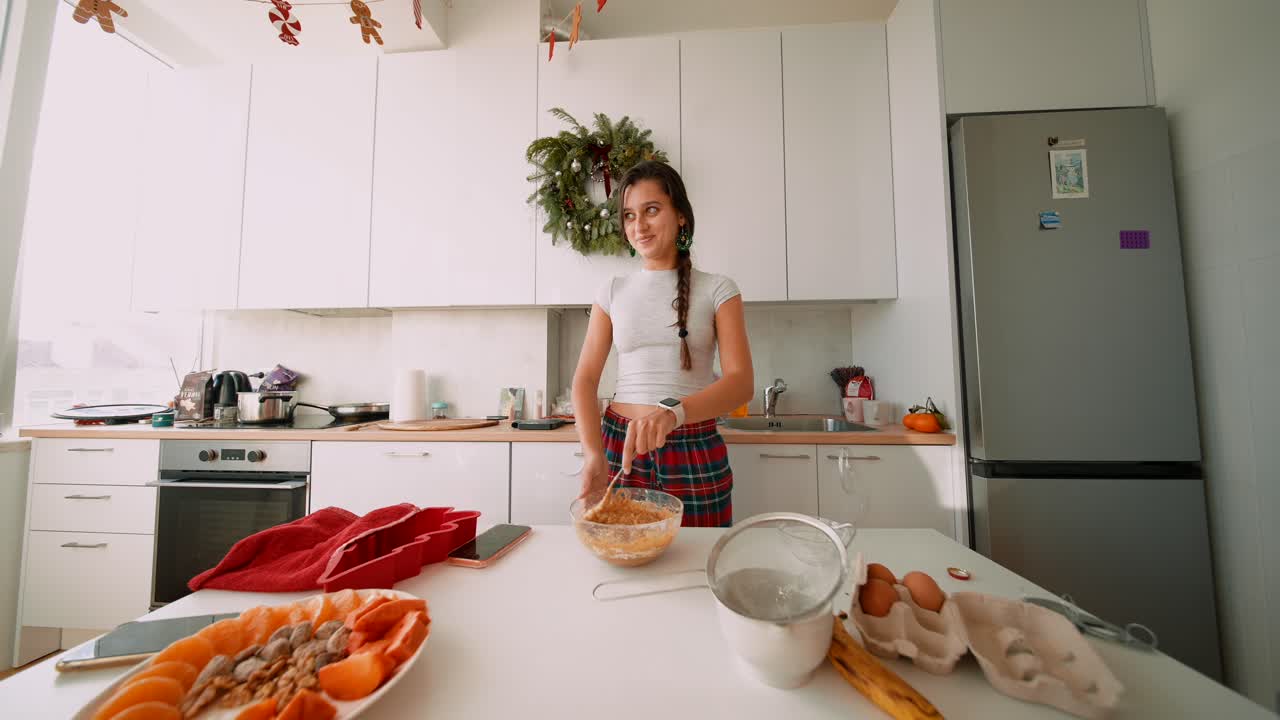 Donna che cucina in cucina con decorazioni natalizie