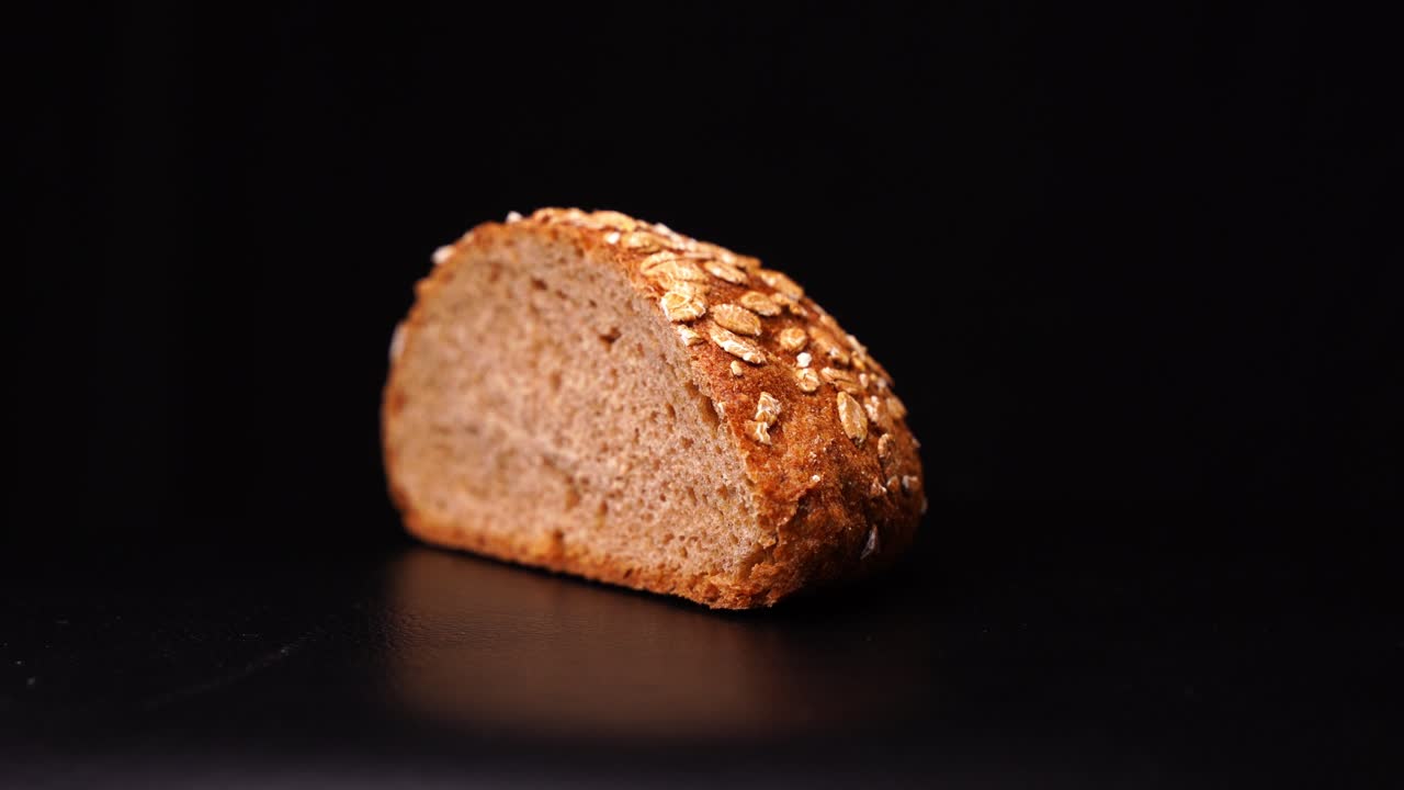 Bread with oatmeal rotates against a black background