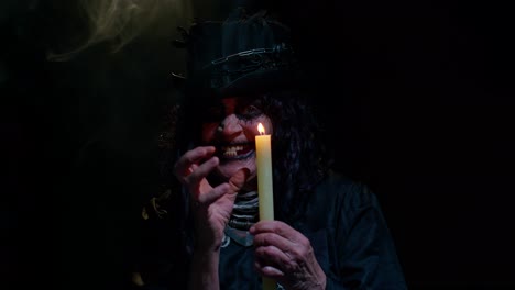 frightening creepy senior woman with halloween witch makeup looking at candle, conjure, hex, wiz