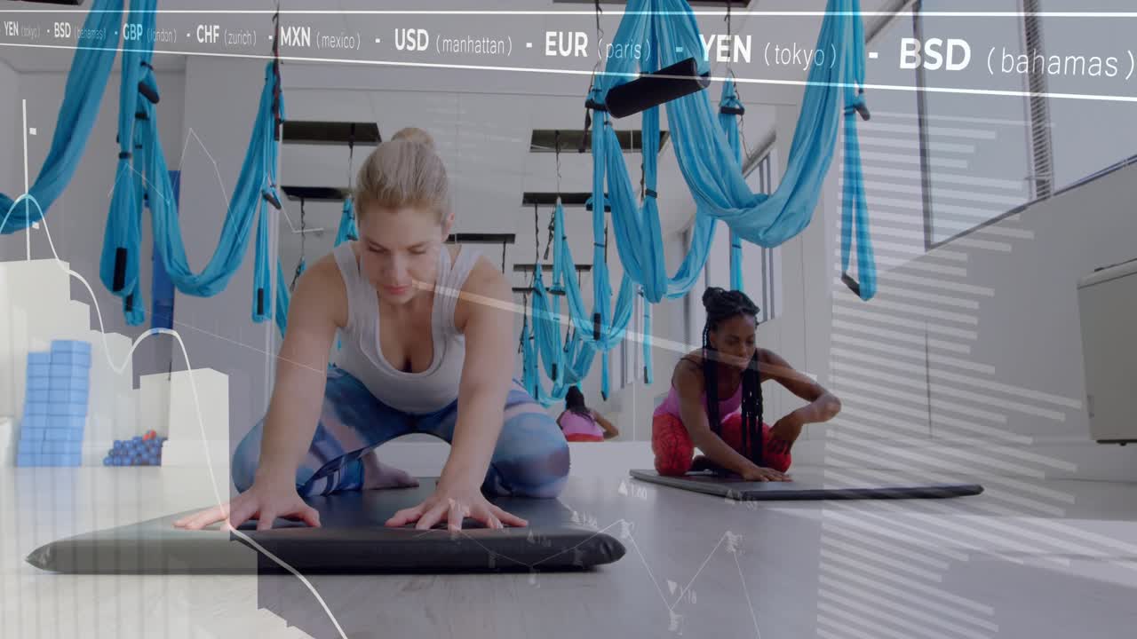 Women doing yoga under hammocks folding forward as finance ticker drifting above holding deep fold
