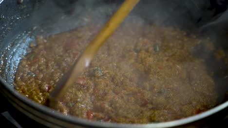 mezcla de cuchara de madera salsa de curry chisporroteante con vapor de vapor que se eleva
