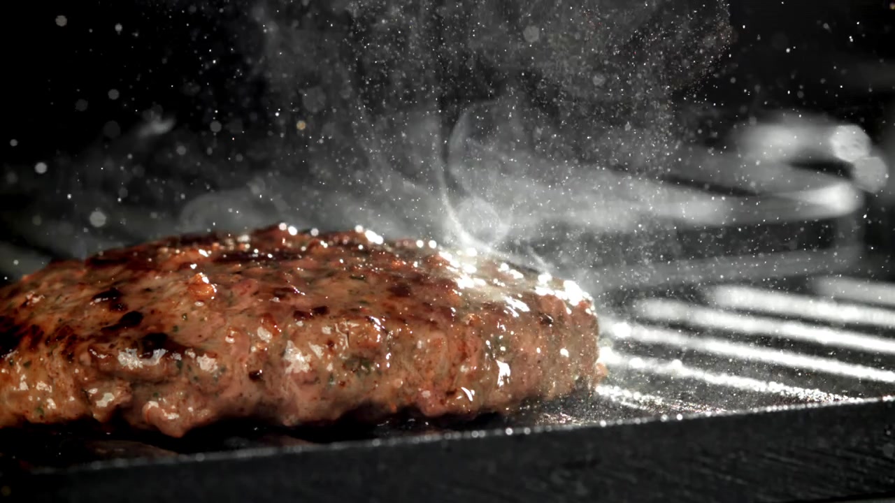 Nærbillede af en saftig hakkebøf, der syder på en varm grill