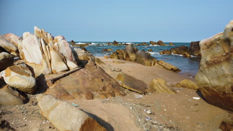 sandy beach with rocks polluted with washed out rubbish, low altitude gimbal