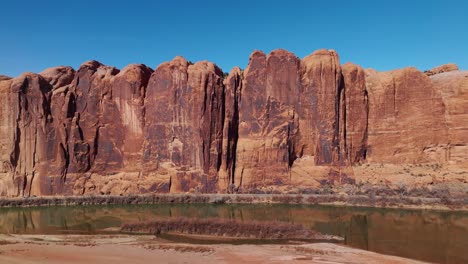 drone strong midday light over moab steep sheer cliff walls, illuminating red sandstone formations