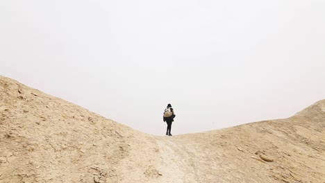 Reisende-Frau,-Die-Durch-Das-Tal-Geht,-Trockene-Wüste,-Neblige-Atmosphäre,-Israel,-Reisender-Schuss