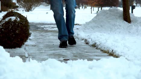 HD-video-clip-of-man-salting-a-concrete-sidewalk-in-a-suburban-neighborhood-in-Michigan-USA,-in-the-winter-right-after-a-winter-storm-winter-life-hack-throw-some-salt-on-the-sidewalk-to-thaw-ice-snow