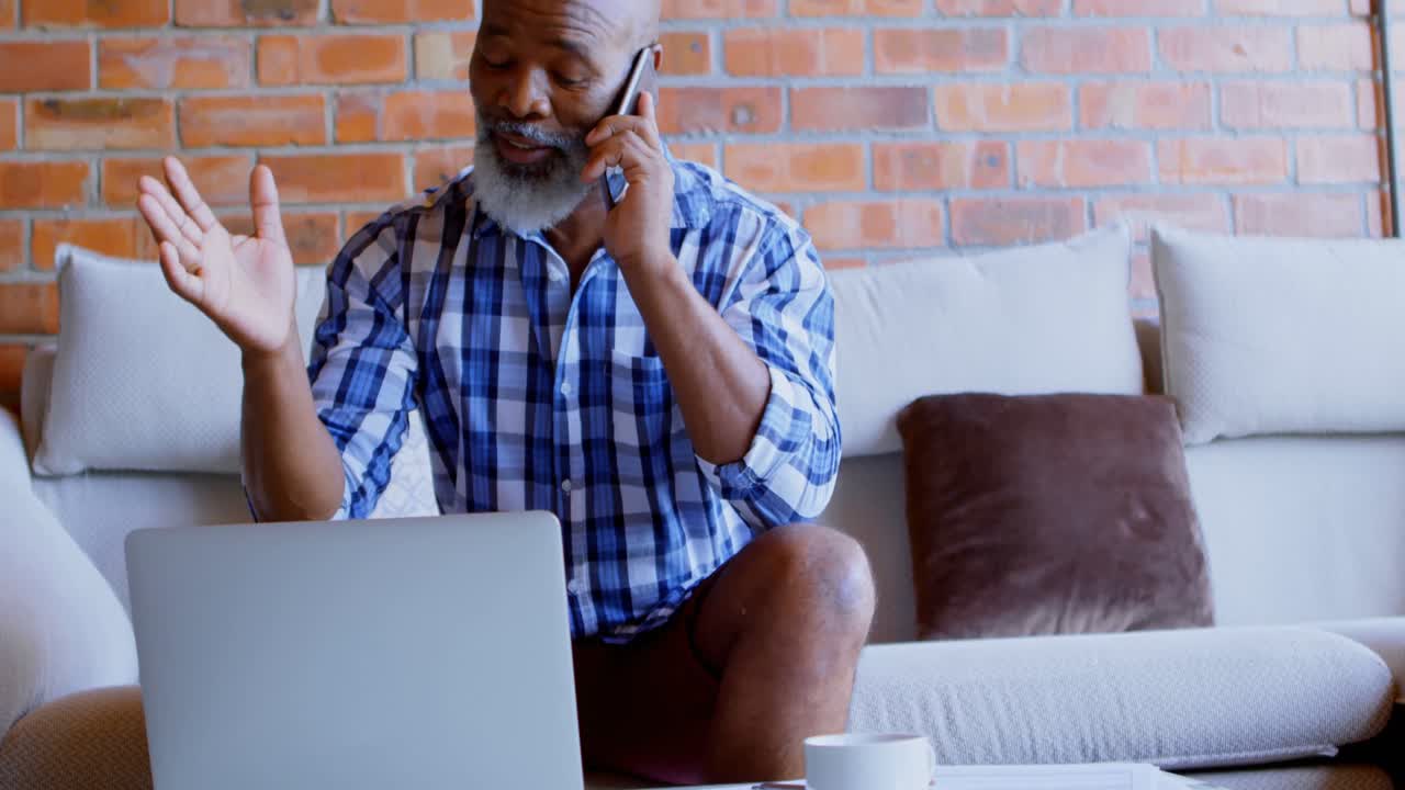 Senior man talking on mobile phone in living room 4k