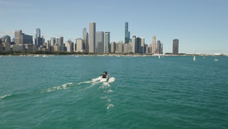 drone flies behind yacht, pan left to reveal chicago skyline on beautiful summer day