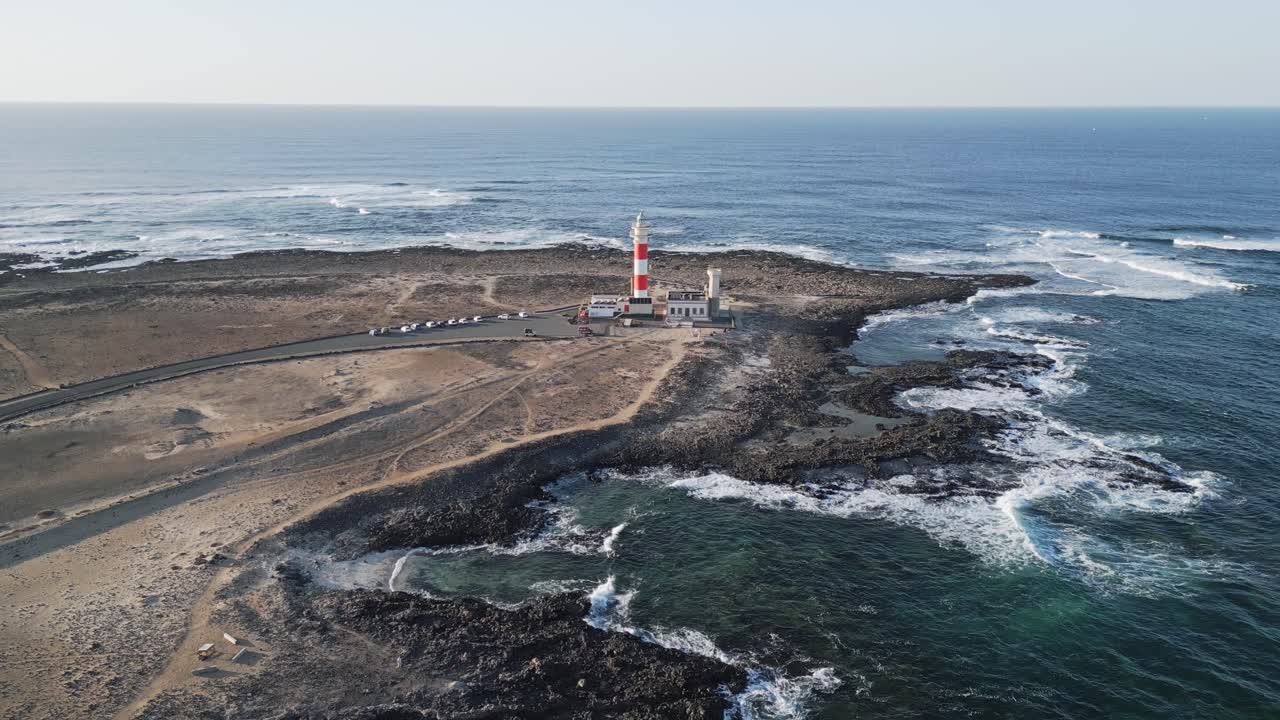 Drone footage of El Tostón Lighthouse in El Cotillo, Fuerteventura, with rocky shoreline, Atlantic waves, and volcanic landscape.