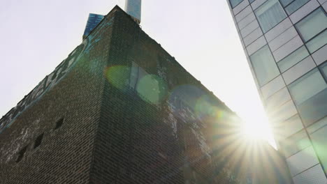 el sol brilla entre un edificio de ladrillo y una torre de oficinas en nueva york.