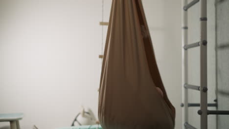 excited toddler boy in t-shirt turns in hammock chair at home