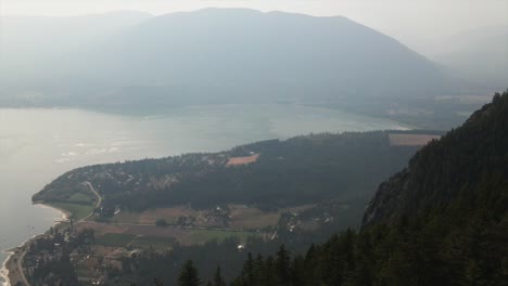 Beautiful-aerial-view-of-a-foggy-lake-surrounded-by-hills-and-forest