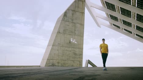 Young-Attractive-Trendy-Man-skateboarding-fast-under-a-solar-panel-on-a-morning-sunny-day-with-an-urban-city-background-in-slow-motion