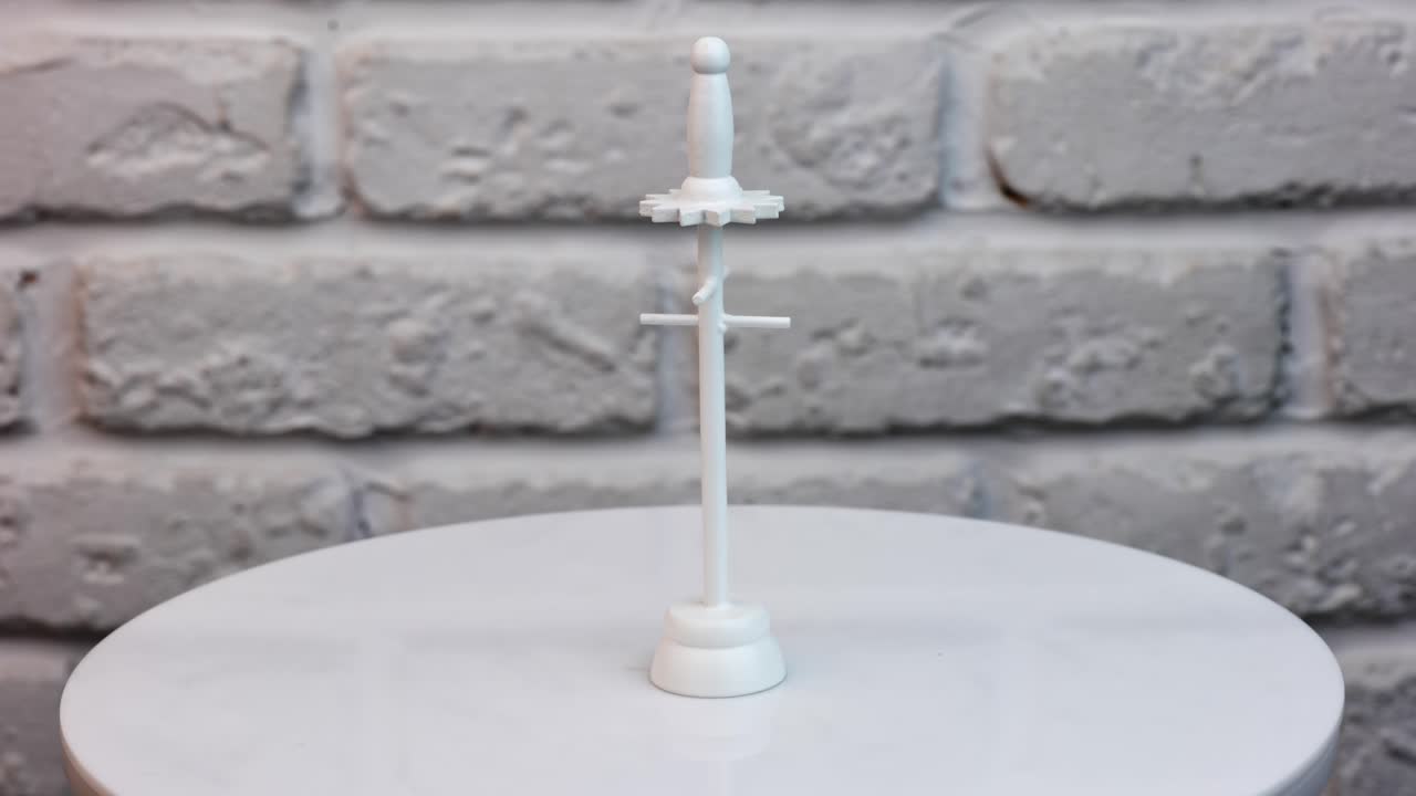 Miniature clothes rack made of wood. White hanger rotating at the table close up. White wall background.