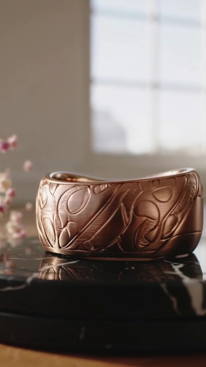 Vertical video: Starting turntable rotating to reveal bronze cuff on marble base, showing motifs