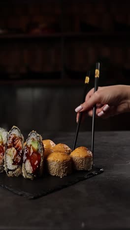 mujer comiendo rollos de sushi con palillos