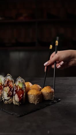 woman eating sushi rolls with chopsticks