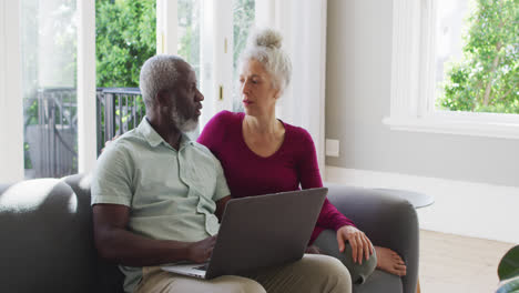 mixed race senior couple using laptop in the living room at home