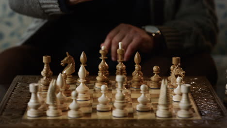 Chess-game-board-closeup.-Senior-man-hand-moving-figure-in-strategy-game.