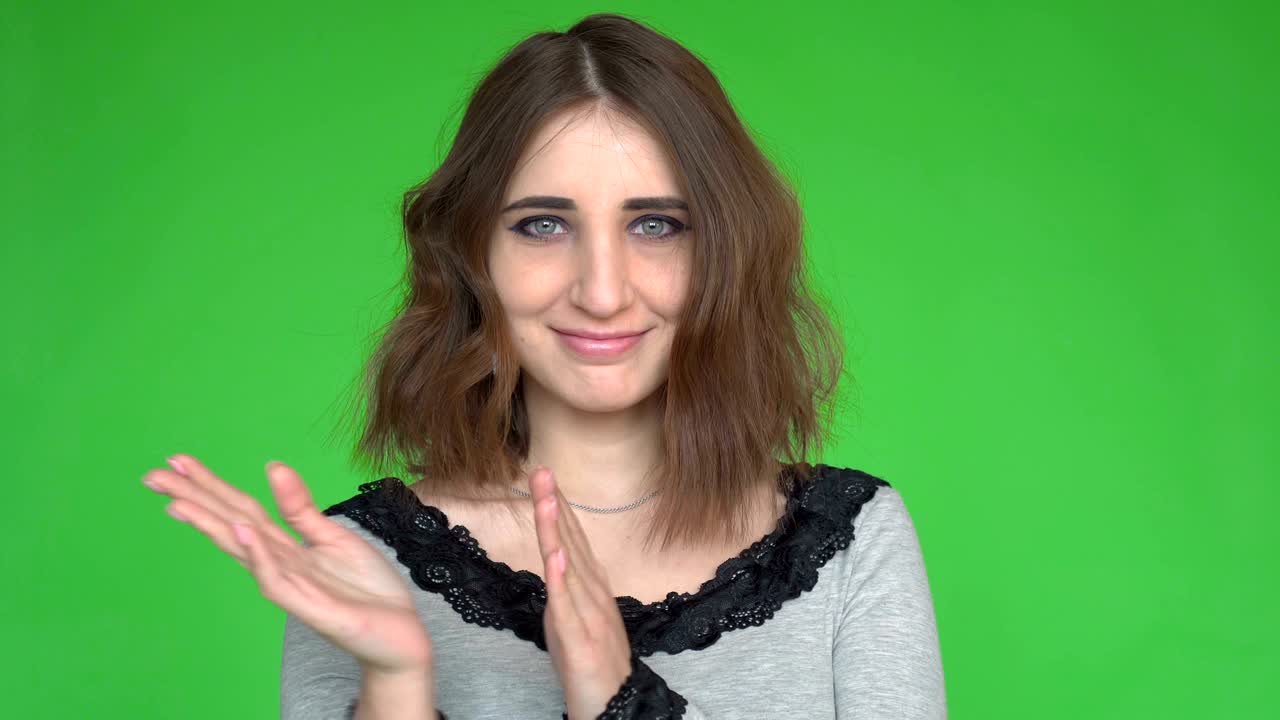 Ritratto di giovane donna felice che applaude su sfondo verde