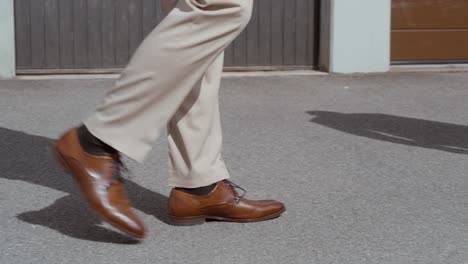 close-up of man walking in brown leather shoes on urban street – elegant business style