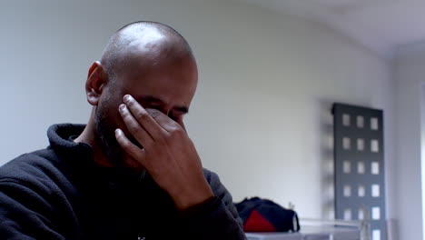 man in a dark shirt feeling stressed with his hand on his forehead in an office setting, shallow focus