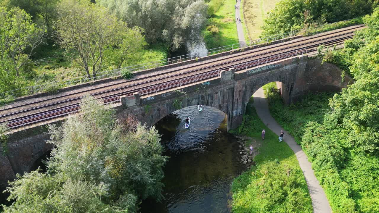 Railway bridge which crossing the Great Stour river with resting people, Canterbury, Kent, England.