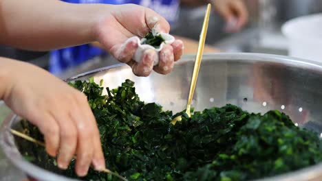 hands making stuffed vegetable rolls in a bowl