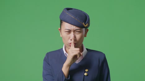 close up of asian woman air hostess looking at camera and making shh gesture in the green screen background studio