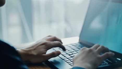 Hands typing on a laptop keyboard in a sunlit office. Business professional engaged in data entry or coding as text and data flow onscreen