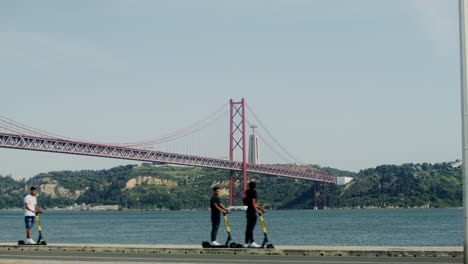 puente 25 de abril en lisboa con scooters eléctricos