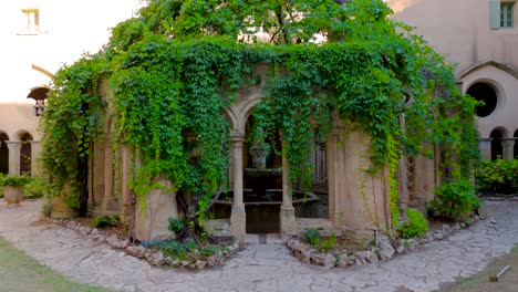 slow establishing shot of a exterior fountain facade covered with vines at a abbey