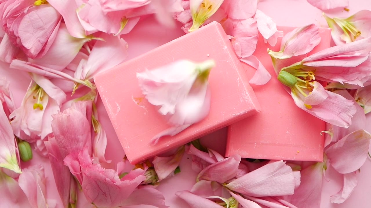 Saponette rosa circondate da petali di fiori che cadono