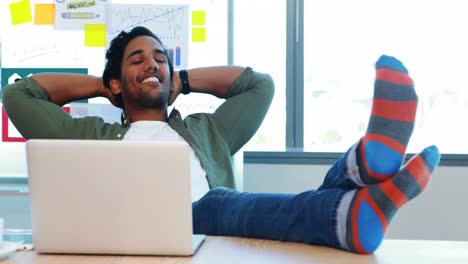 Male-executive-relaxing-with-feet-up-at-desk