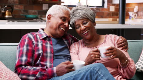 Lächelndes-älteres-Paar,-Das-Sich-Zu-Hause-Mit-Einem-Heißen-Getränk-Auf-Dem-Sofa-Entspannt