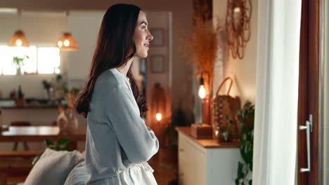 mujer mirando por una ventana en una acogedora sala de estar