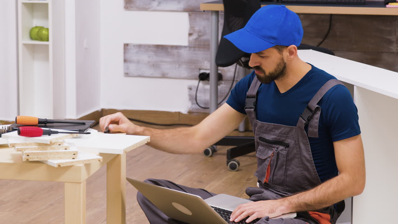 Man Assembling Furniture with Laptop