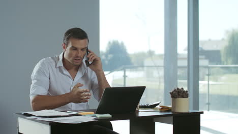 Hombre-De-Negocios-Trabajando-En-Una-Computadora-Portátil.-Hombre-Concentrado-Hablando-Por-Teléfono-Móvil.