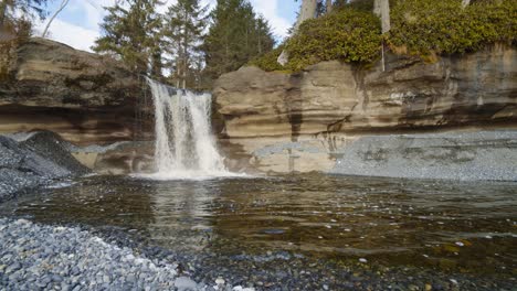 awesome small waterfall with crystal clear waters flowing between sandstone walls in sandcut beach, vancouver island, bc - static shot