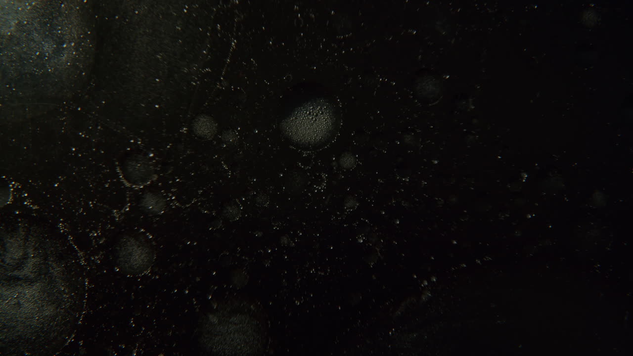 투명한 표면에서 빛나기 시작하는 작은 기포의 매크로 샷