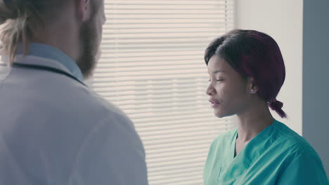 a cute young american nurse talks with a young doctor with long, blond hair