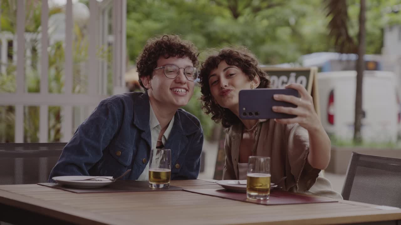 Young couple taking fun selfies at an outdoor cafe