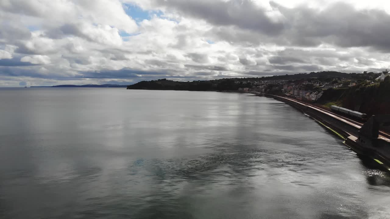 Coastline aerial view showcasing seawall, tranquil waters, and distinctive geography of Dawlish, Devon. rising shot