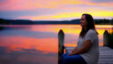 woman sitting on a pier at sunset