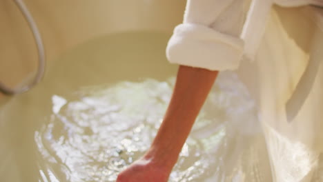 hands of biracial woman with vitiligo preparing bath