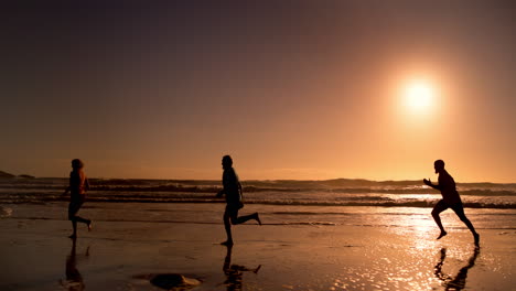 people running on the beach at sunset