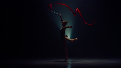 flexible sportswoman spinning ribbon. gymnast practicing rhythmic gymnastics